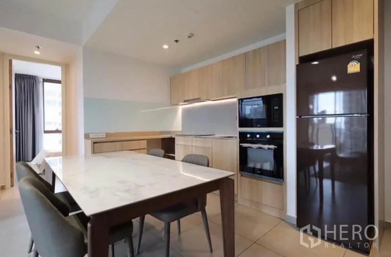 คอนโด ให้เช่าในWatthana, Bangkok - ครัวสมัยใหม่ตู้ไม้สีอ่อน โต๊ะทานอาหารหินอ่อน เตาอบบิวท์อินและตู้เย็น