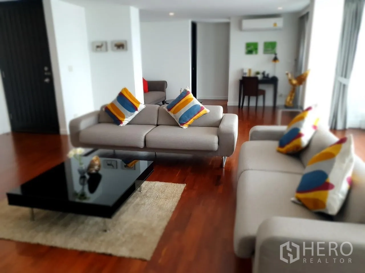 Apartment for rent in Bang Rak, Bangkok - Main lounge with two light sofas, colorful cushions and sleek black coffee table.