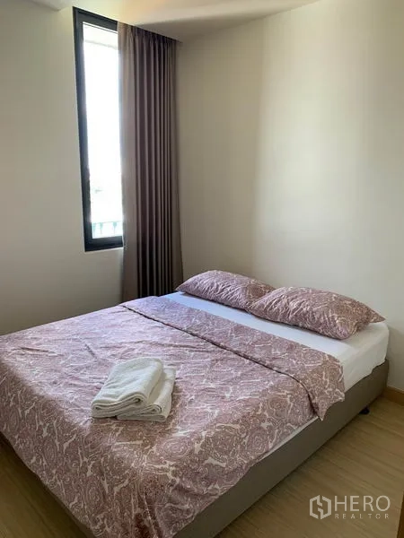 Condominium for rent in Watthana, Bangkok - Second bedroom with tall window, blackout curtains and a double bed with folded towels.
