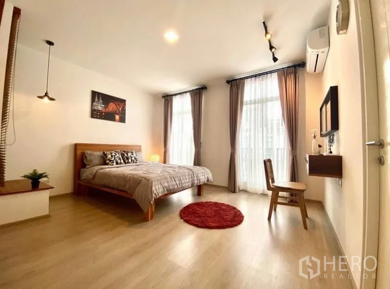 ทาวน์เฮาส์ ให้เช่าในBang Phli, Samut Prakan - ห้องนอนมาสเตอร์กว้าง เตียงไม้ หน้าต่างบานใหญ่ ผ้าม่านโปร่ง และประตูระเบียง