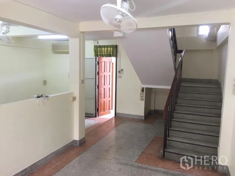 Townhouse for rent in Khlong Toei, Bangkok - Open-plan ground floor with staircase, ceiling fans and natural light.