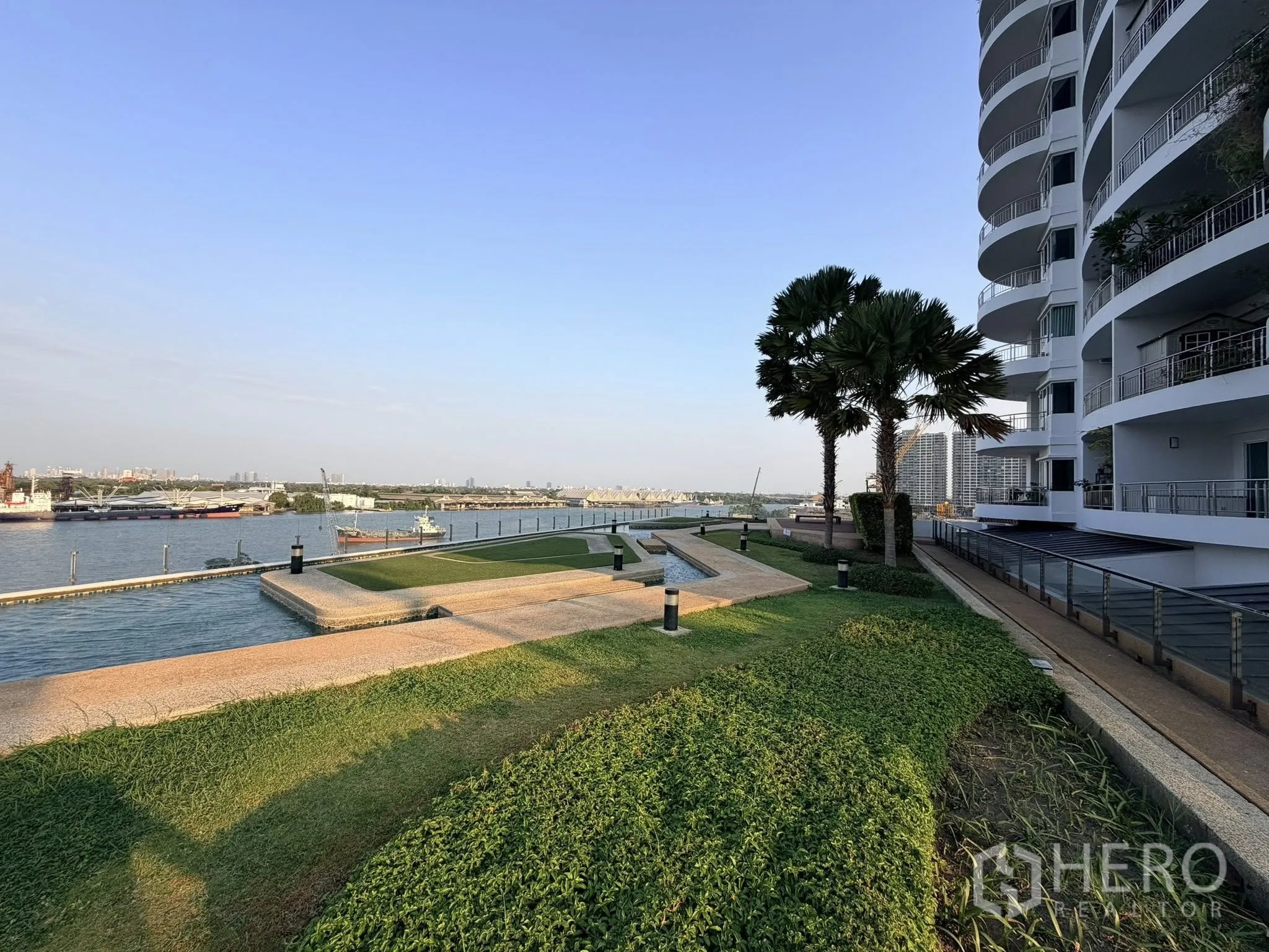 Home Office for rent or sale in Yan Nawa, Bangkok - Landscaped riverside promenade beside a modern building with wide water views.