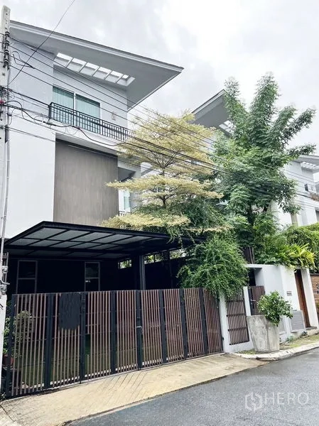 Townhouse for rent or sale in Don Mueang, Bangkok - Modern three-storey townhouse exterior with gated fence, covered carport and mature trees in Don Mueang.