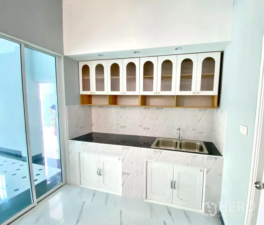 工厂 出租或出售在Bang Bua Thong, Nonthaburi - 紧凑厨房，吊柜、黑色台面与双槽水盆。