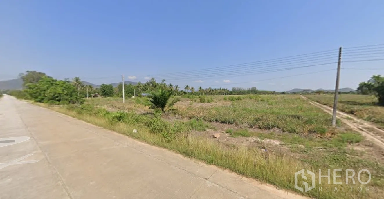 Land for sale in Mueang Prachuap Khiri Khan, Prachuap Khiri Khan - Corner view showing paved access, grassed plots and nearby palms.