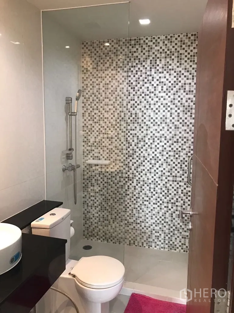 Condominium for rent in Watthana, Bangkok - Second bathroom featuring a walk-in shower with mosaic tile wall, toilet and countertop basin.