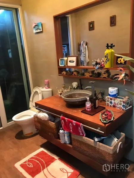 独立式住宅 出售在Lat Phrao, Bangkok - 卫生间设台上盆与木质台面、大镜子及马桶。