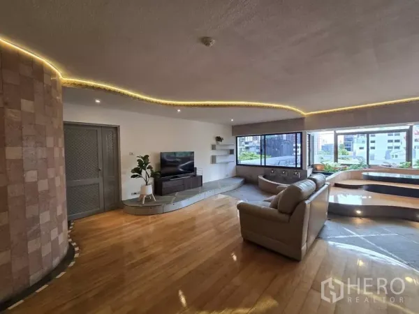 Condominium for rent in Pathum Wan, Bangkok - Spacious living room with curved cove lighting, large windows, TV console and city views.