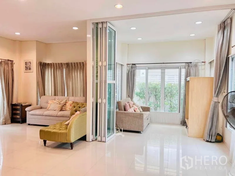 บ้าน ให้เช่าในLat Krabang, Bangkok - ห้องครอบครัวสว่าง กั้นด้วยประตูกระจกพับได้ และหน้าต่างบานใหญ่รับวิวสวน