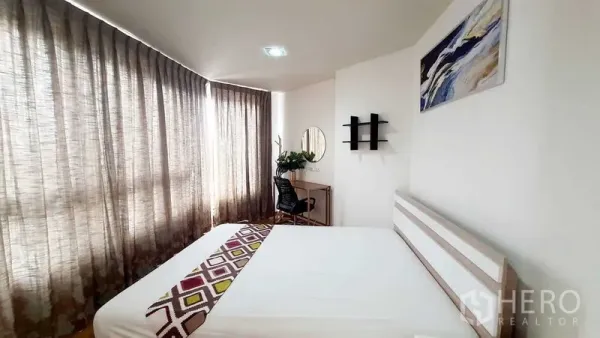 Condominium for sale in Bang Kho Laem, Bangkok - Sunlit bedroom with double bed, study desk and floor-to-ceiling curtains.
