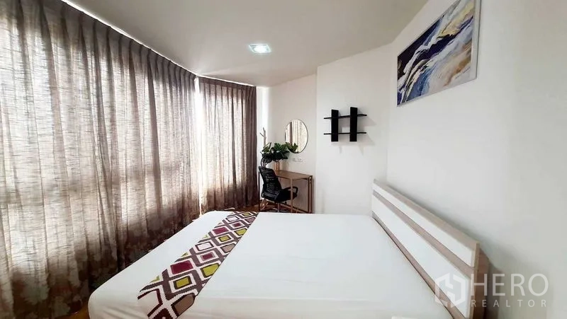 Condominium for sale in Bang Kho Laem, Bangkok - Sunlit bedroom with double bed, study desk and floor-to-ceiling curtains.