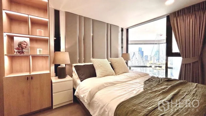 Condominium for rent - Bedroom with upholstered headboard, illuminated built-in shelving and city-view window.