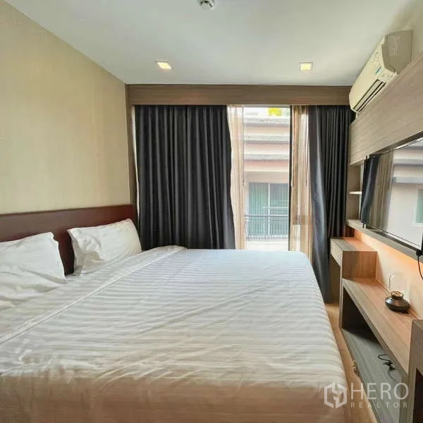 คอนโด ให้เช่า - ห้องนอนเตียงคิงพร้อมทีวีติดผนังและทางออกระเบียง