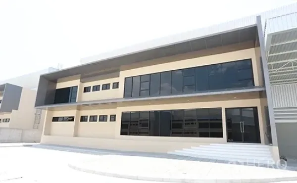 Warehouse for rent in Bang Pakong, Chachoengsao - Modern two-storey warehouse and office facade with dark glass windows and canopy in Bang Pakong.