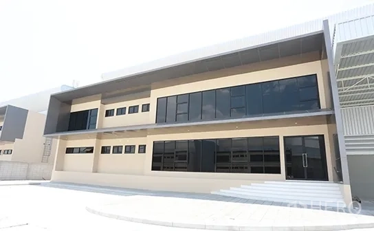 Warehouse for rent in Bang Pakong, Chachoengsao - Modern two-storey warehouse and office facade with dark glass windows and canopy in Bang Pakong.