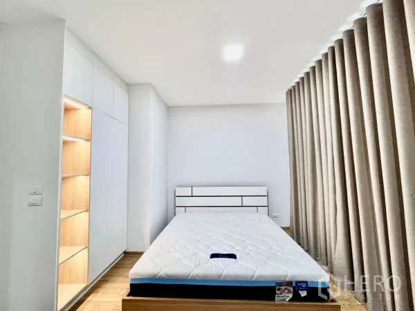 Townhouse for rent in Bang Phli, Samut Prakan - Master bedroom with floor-to-ceiling curtains, built-in wardrobe, and illuminated shelving.
