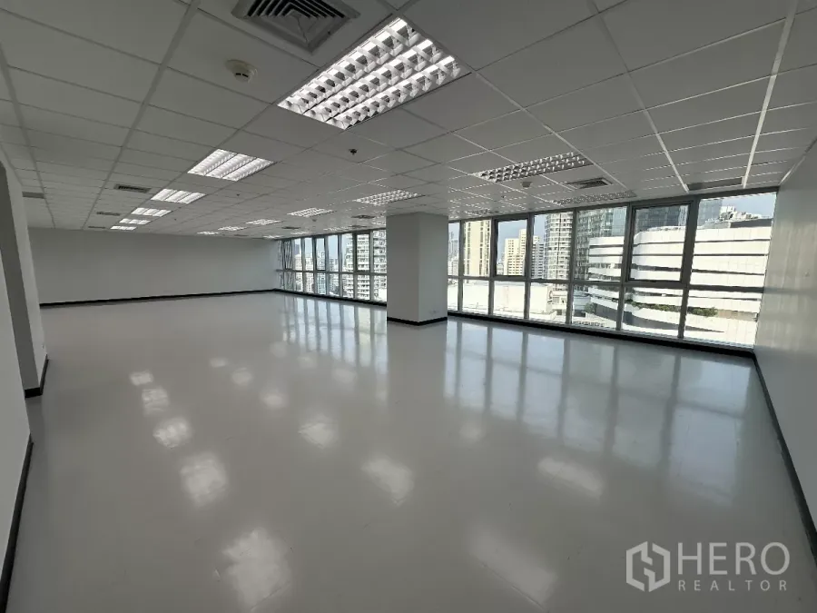 Office Space for rent in Watthana, Bangkok - High-floor open-plan office with full glass windows and Bangkok skyline views under bright grid ceiling lights.