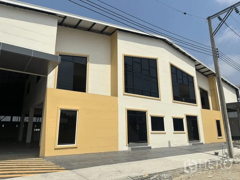 Warehouse for rent in Bang Pakong, Chachoengsao - Front facade of new warehouse with tinted windows, paved frontage and a covered loading bay.