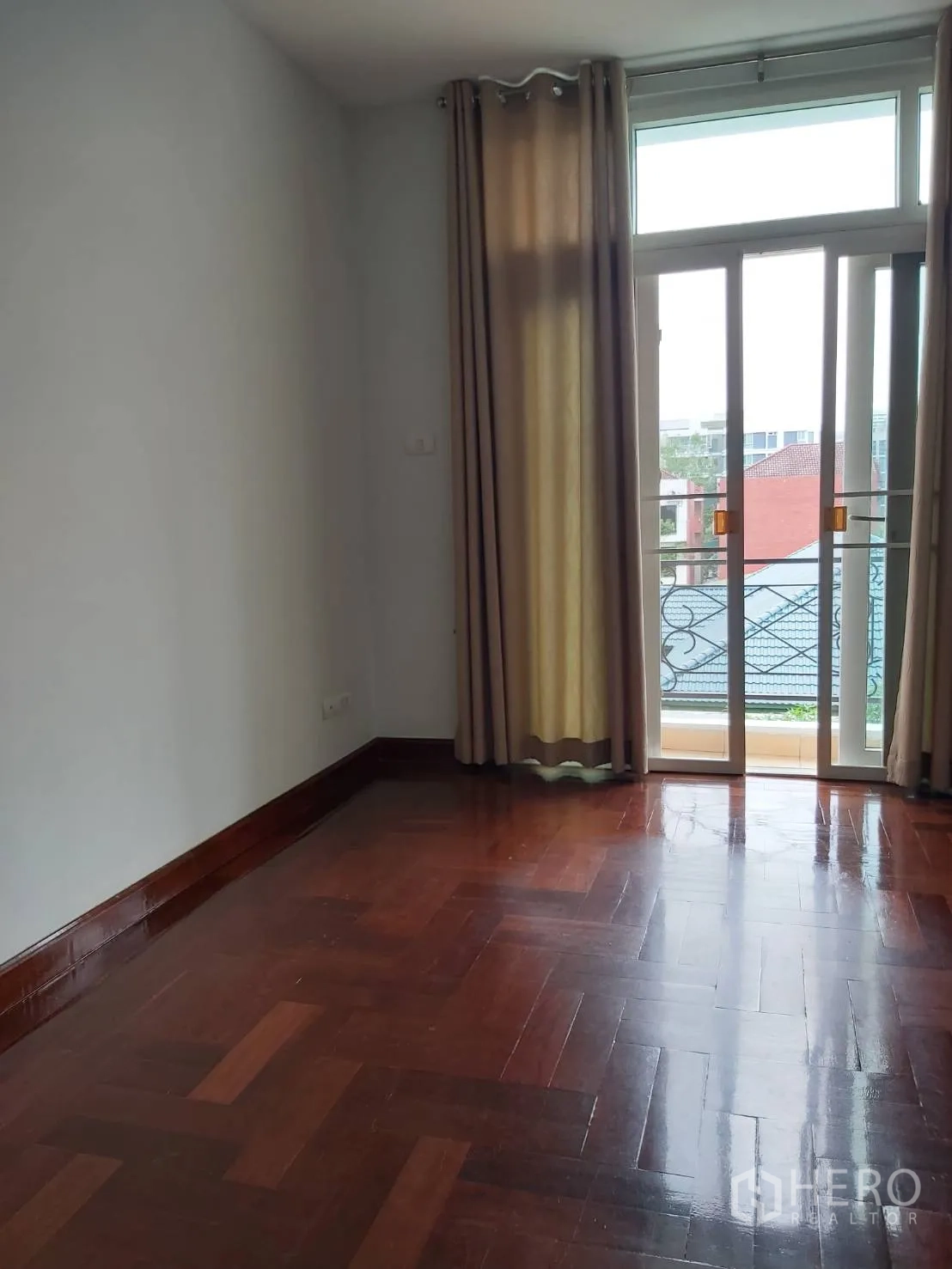 Apartment for rent in Khlong Toei, Bangkok - Spacious empty room with balcony doors, beige curtains, and polished parquet floor.