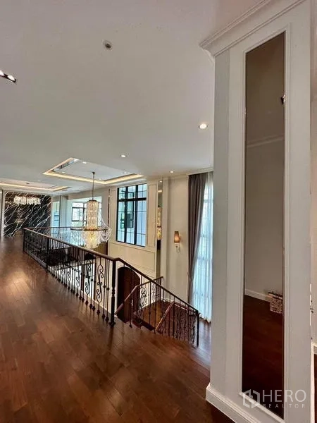 Detached House for sale - Upper landing with wood floors, iron staircase and chandelier, lit by large windows.