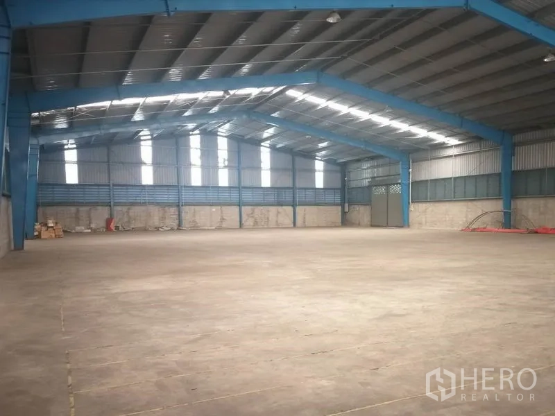 Warehouse for rent in Pathum Thani - Open clear-span space with blue steel columns and ventilated wall panels.