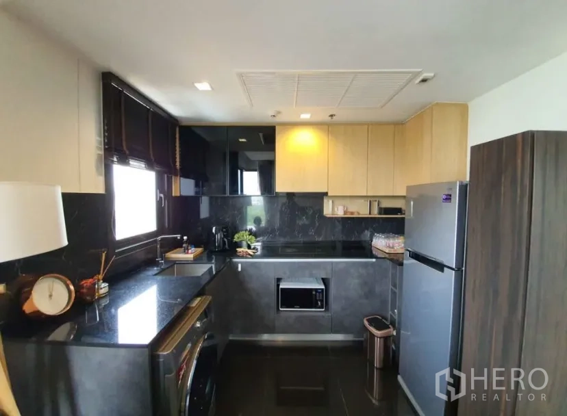 Condominium for rent in Chatuchak, Bangkok - Contemporary kitchen with dark stone countertops, cabinets and a stainless fridge.