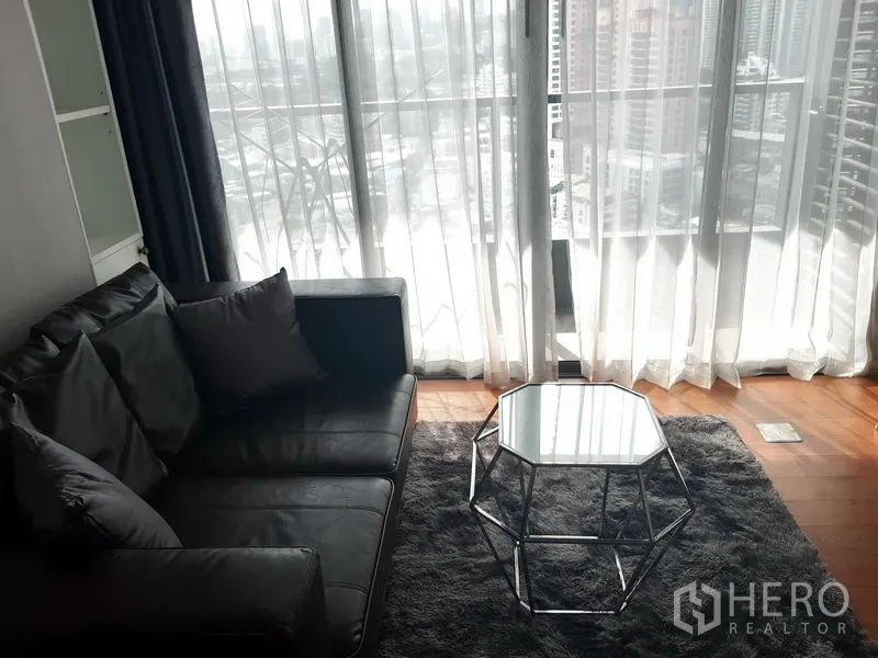 คอนโด ให้เช่าในKhlong Toei, Bangkok - ห้องนั่งเล่นสว่าง โซฟาหนัง พรมฟู และหน้าต่างเต็มบานมองเห็นวิวเมือง