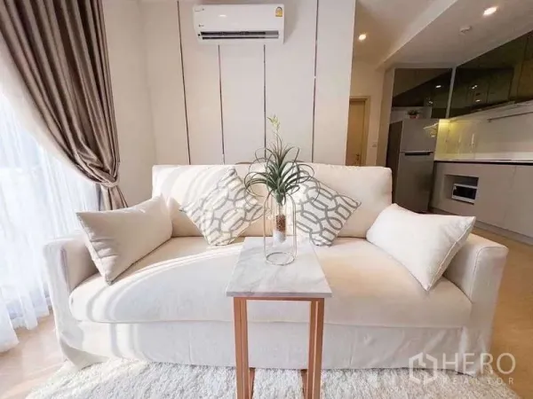 Condominium for rent or sale in Watthana, Bangkok - Bright lounge with a white fabric sofa, accent pillows, marble side table, and air conditioner.