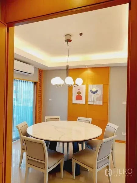 อพาร์ทเมนท์ ให้เช่า - ห้องอาหารสว่าง โต๊ะกลมหินอ่อน เก้าอี้หกตัว และโคมไฟแขวนดีไซน์โมเดิร์น