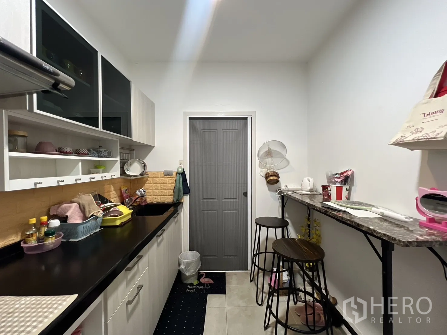 บ้าน ให้เช่าหรือขายในLat Krabang, Bangkok - ครัวแยกสไตล์แกลเลย์ ตู้ลอย ท็อปหินสีดำ และเคาน์เตอร์บาร์พร้อมสตูล