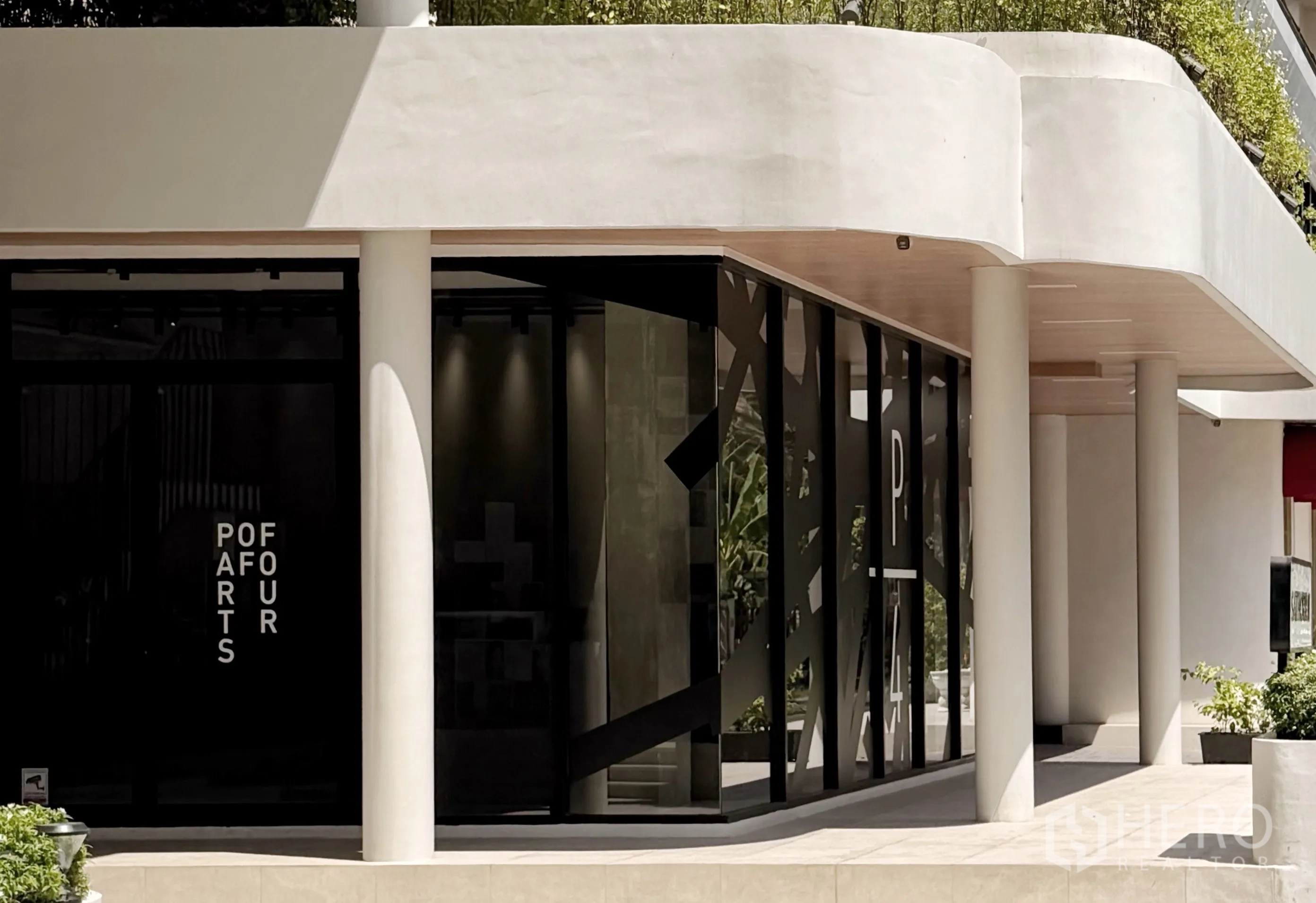 Retail Space for rent in Sathon, Bangkok - Close-up of retail shopfront with tall glass windows, white columns, a covered walkway, and greenery.