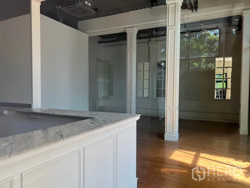 零售空间 出租在Khlong Toei, Bangkok - 接待区配大理石柜台、白色线板立柱与木地板，外露天花