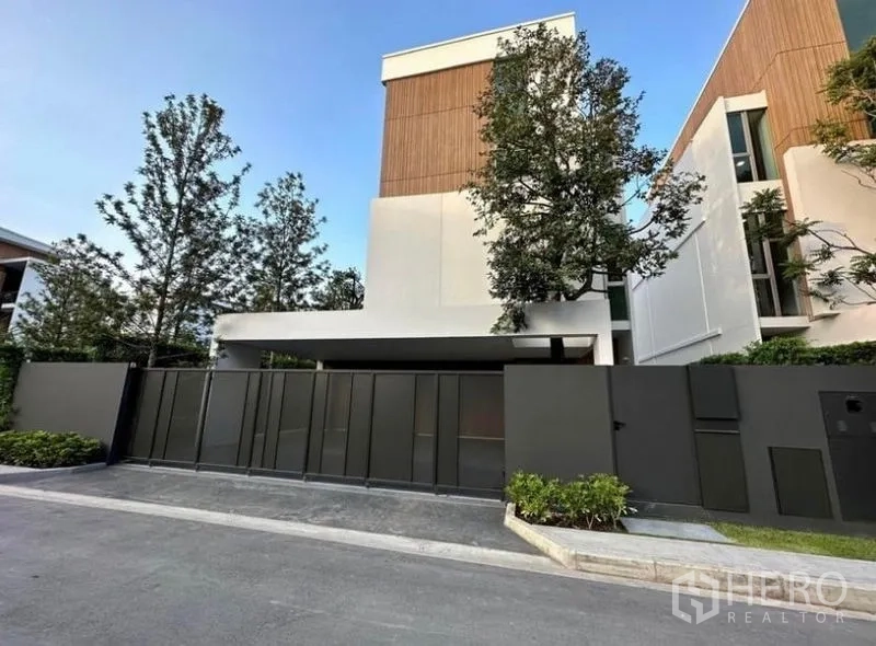 Detached House for rent - Modern detached house facade in Saphan Sung, Bangkok with tall privacy gate and trees.