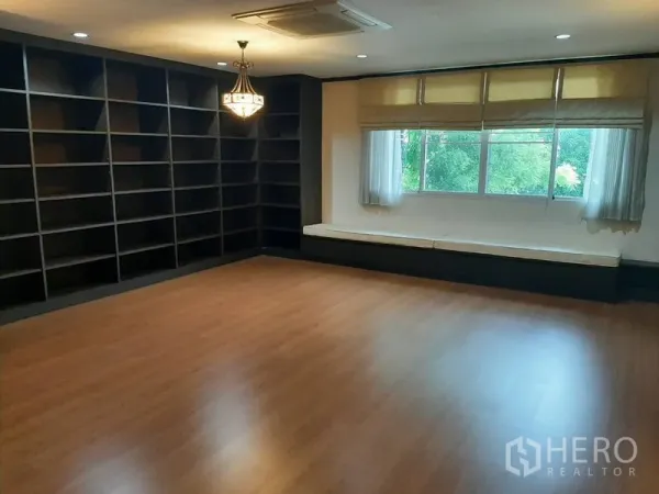 Home Office for sale in Phra Khanong, Bangkok - Large multipurpose room with wood flooring, wall-to-wall shelving and a window seat.
