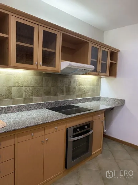 Condominium for rent - Fitted kitchen with wood cabinets, granite counters, electric cooktop, built-in oven and tiled backsplash.