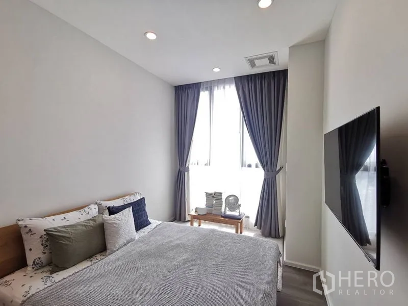 公寓 出售在Phra Khanong, Bangkok - 温馨卧室，双人床、落地窗、遮光窗帘与壁挂电视。