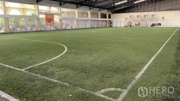 Warehouse for rent in Phra Pradaeng, Samut Prakan - Large covered indoor turf field under a steel truss roof within the complex.