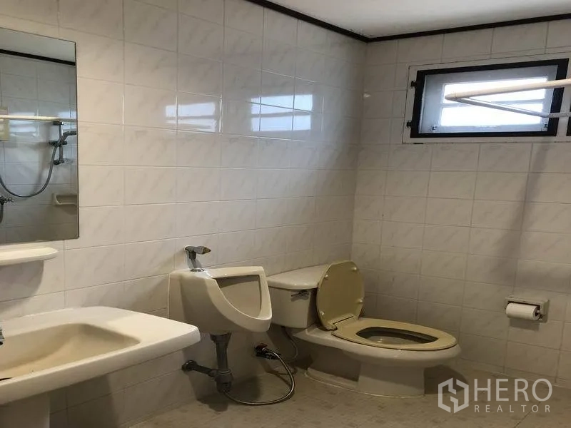 Detached House for rent - Fully tiled bathroom with sink, toilet, urinal and a small window.