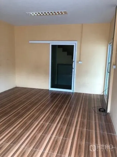 Warehouse for rent in Pak Kret, Nonthaburi - Ground-floor office room with wood-look tile flooring and a sliding glass door.