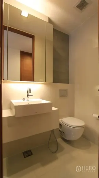 Condominium for rent in Khlong Toei, Bangkok - Bright bathroom with floating vanity, mirrored cabinet and wall-hung toilet.