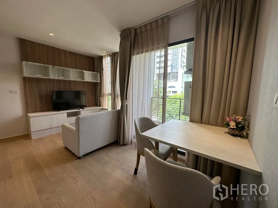 公寓 for rent in Watthana, Bangkok - 客厅设电视柜与书桌，落地窗配窗帘，可见绿意景观。
