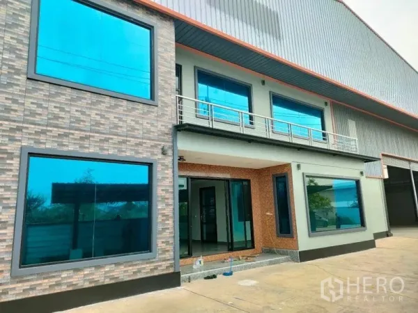 工厂 出租在Ban Phaeo, Samut Sakhon - 现代化工厂立面，蓝色大窗与高卷闸门。