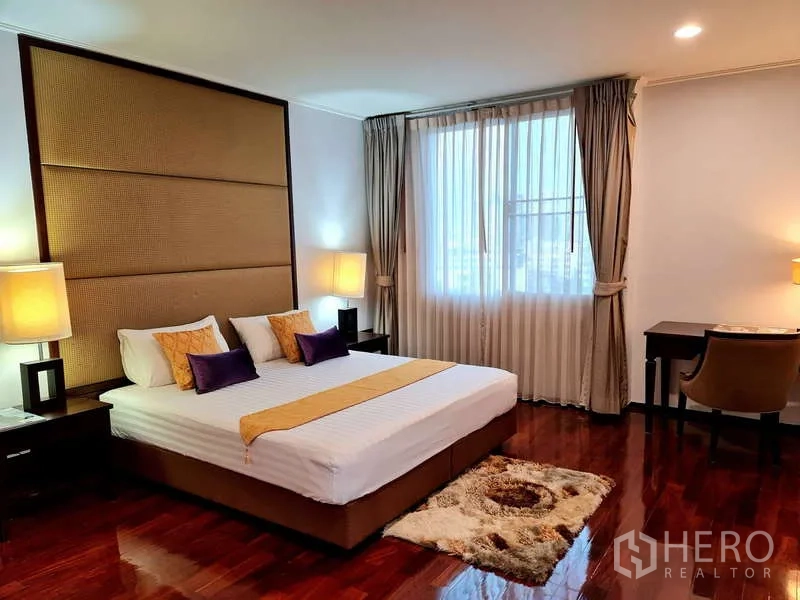 อพาร์ทเมนท์ ให้เช่า - ห้องนอนหลักเตียงคิง หัวเตียงขนาดใหญ่ โต๊ะทำงาน และหน้าต่างรับแสง