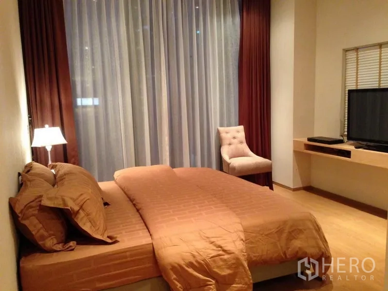 公寓 出售在Bang Rak, Bangkok - 主卧配大床、纱帘与遮光窗帘、单椅及电视。