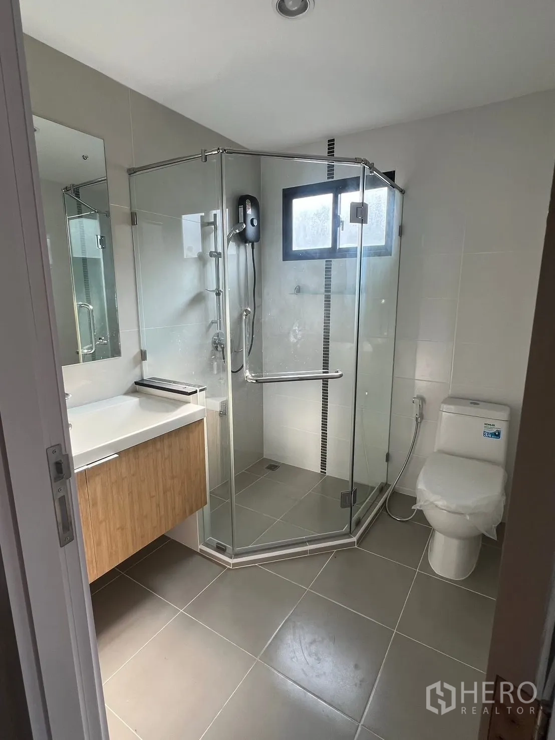 Detached House for rent in Bang Phli, Samut Prakan - Modern bathroom with glass shower enclosure, window, vanity and toilet in a Bang Phli detached house.
