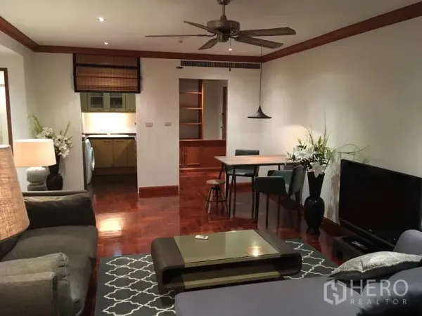 公寓 出租在Sathon, Bangkok - 开放式客餐厅，木地板、吊扇与电视柜，可望向独立厨房。