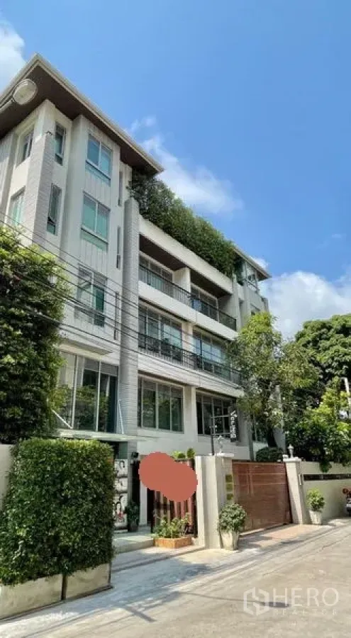 Office Space for rent in Khlong Toei, Bangkok - Modern low-rise office building exterior with balconies, greenery and a secure gate under a blue sky.