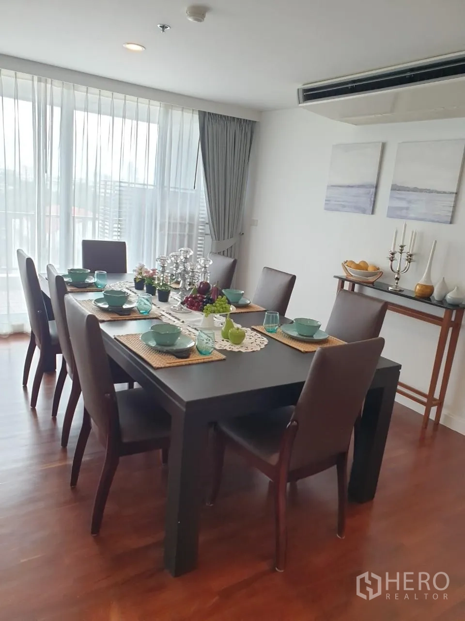 Apartment for rent in Bang Rak, Bangkok - Formal dining area set for eight beside floor-to-ceiling windows.