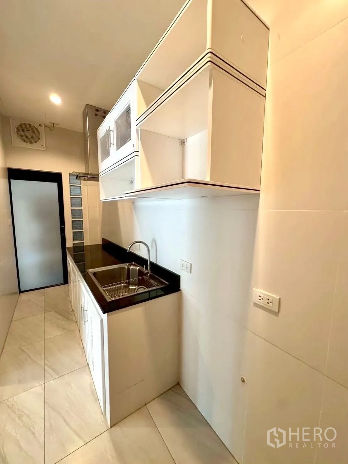 Home Office for rent in Wang Thonglang, Bangkok - Compact galley kitchen with upper cabinets, black countertop, and sink.