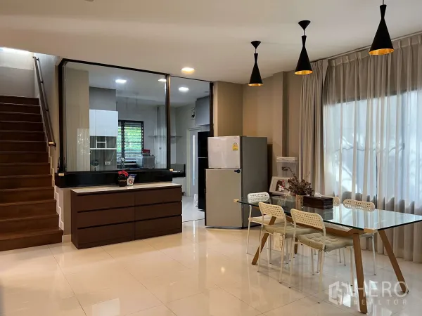 Detached House for rent in Prawet, Bangkok - Dining area with glass table, pendant lights and stairs beside floor-to-ceiling curtains.